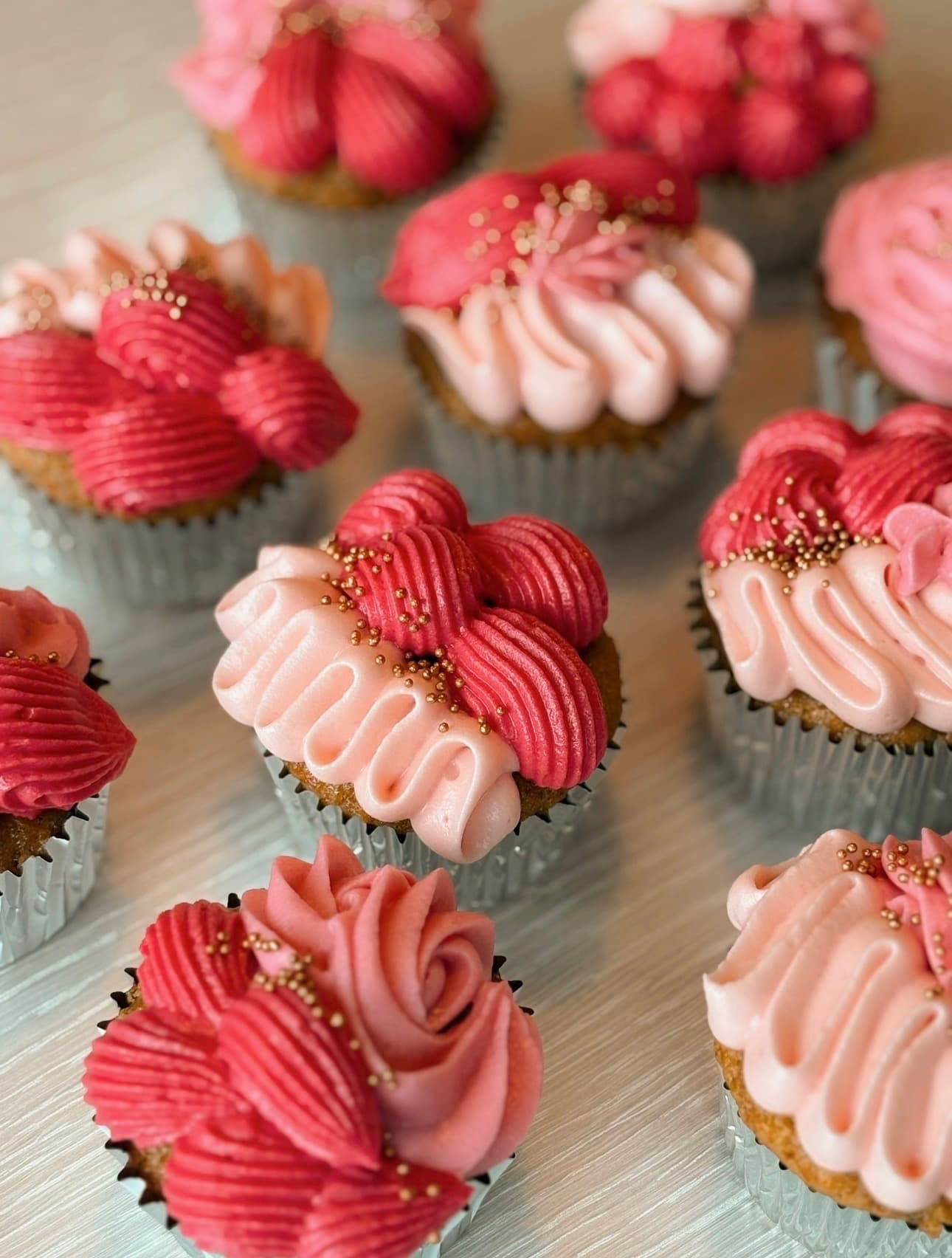 Cupcakes med rosa smørkrem-rosetter og små gullkuler, nærbilde